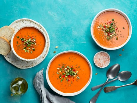 Gaspacho soup on blue tabletop. Three bowls of traditional spanish cold soup puree gaspacho or gazpacho on bright blue background with copy space for text. Top view or flat lay.