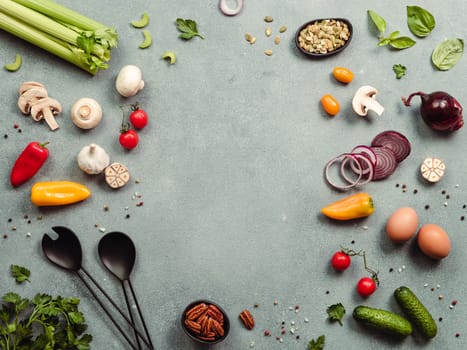 Food ingredients, salad serving utensils with copy space for text or design in center. Various of vegetarian cooking ingredients on gray background. Top view or flat lay