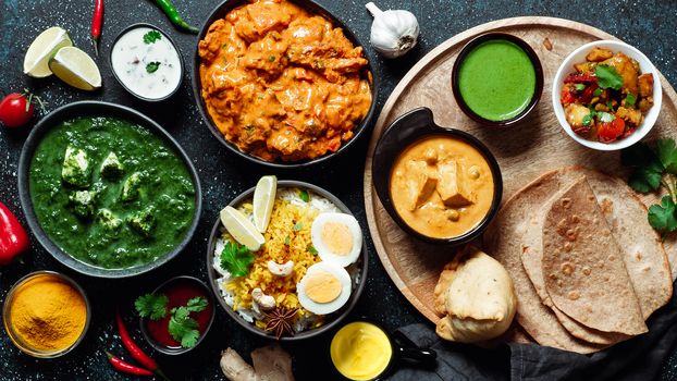 Indian cuisine dishes: tikka masala, paneer, samosa, chapati, chutney, spices. Indian food on dark background. Assortment indian meal top view or flat lay.