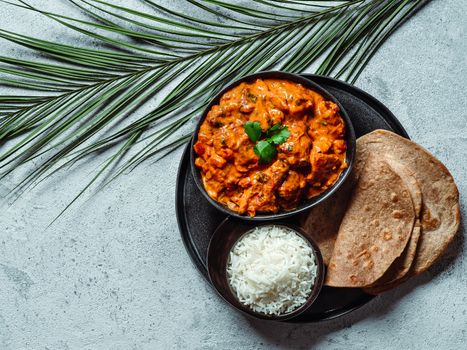 Indian cuisine dishes: tikka masala, rice, samosa, chapati,. Indian food on gray stone background with copy space. Assortment indian meal top view or flat lay.