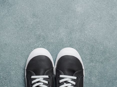 pair of new kids or adult sneakers on gray stone background, top view. Flat lay gray and yellow or mustard color sneakers shoes with copy space for text or design.