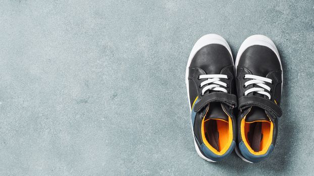 pair of new kids or adult sneakers on gray stone background, top view. Flat lay gray and yellow or mustard color sneakers shoes with copy space for text or design.