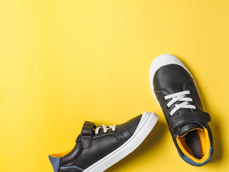 pair of new kids or adult sneakers on yellow background, top view. Flat lay gray and yellow or mustard color sneakers shoes on colorful bright background with copy space for text or design