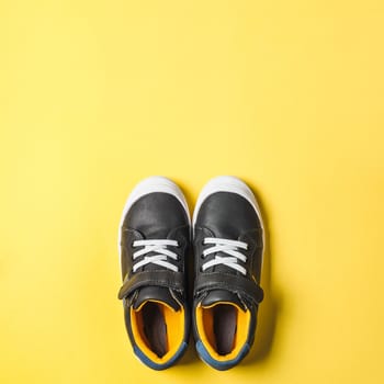 pair of new kids or adult sneakers on yellow background,top view. Flat lay gray and yellow or mustard color sneakers shoes on bright background with copy space for text or design. Square format