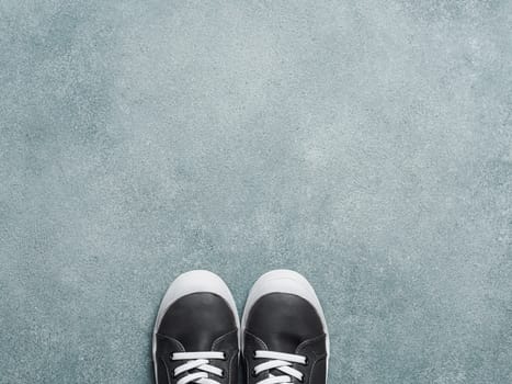 pair of new kids or adult sneakers on gray stone background, top view. Flat lay gray and yellow or mustard color sneakers shoes with copy space for text or design.