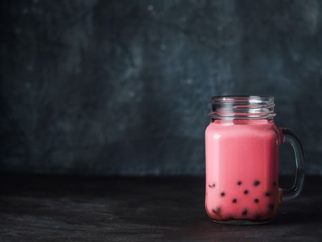 Homemade Milk Bubble Tea with Tapioca Pearls balls. Popular Taiwan bubble tea in glass mason jar with copy space for text. Bubble tea on dark background.