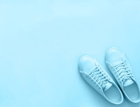 Blue leather sneakers on blue background. Pair of blue sport shoes or sneakers with copy space for text or design. Overhead shot of new blue sneakers, monochrome. Top view or flat lay