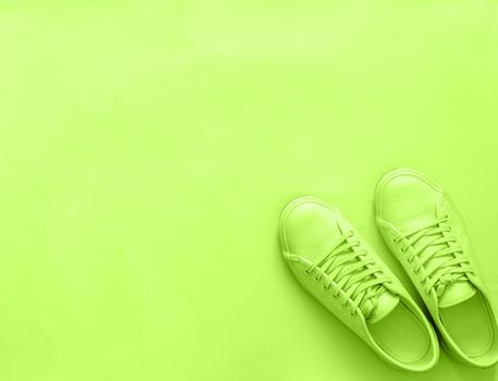 Green neon leather sneakers on green background. Pair of fashion trendy green sport shoes sneakers with copy space for text or design. Overhead shot of new green sneakers,monochrome.Top view, flat lay