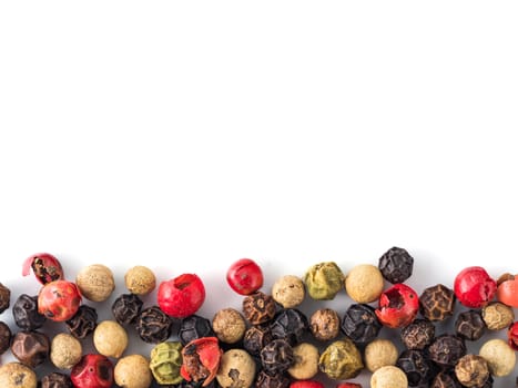 Mixed peppercorns background with white copy space in center. Food background with peppercorns. Different colored peppercorns pattern on white background, top view or flat lay