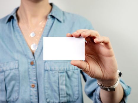 Female hand hold blank white card mockup. Plain call-card mock up template holding woman arm. Caucasian woman in casual blue denim shirt with business card display front. Check offset card design
