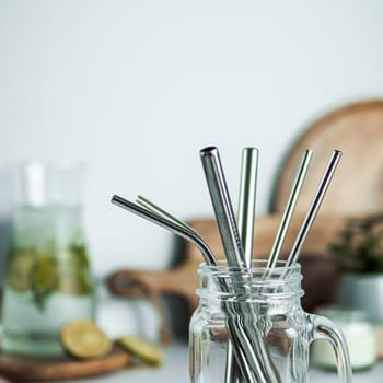 Metal drinking straws in glass mason jar indoor. Metal straws on table on kitchen table. Recyclable straws, zero waste concept.