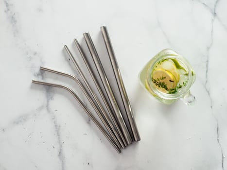 Metal drinking straws and cold drink in glass mason jar on white marble background. Top view or flat lay. Recyclable straws, zero waste concept. Banner.