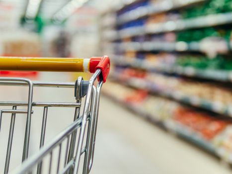 Shopping cart in supermarket. Part of shopping trolley in supermarket aisle. Blurred shelves in grocery store and trolley. Copy space for text or design.