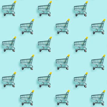 Shopping cart staggered on blue background. Seamless pattern. Top view or flat lay. Shop trolley seamless pattern as sale, discount, shopaholism concept. Consumer society trend.
