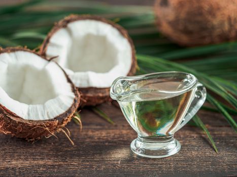 Liquid coconut MCT oil and halved coco-nut on wooden table. Health Benefits of MCT Oil. MCT or medium-chain triglycerides, form of saturated fatty acid.