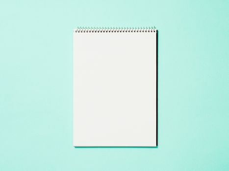 Paper notebook. Empty paper sketchbook on blue background. Top view or flat lay. Copy space for text or design.