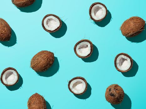 Creative layout of coconuts half on blue background. Tropical pattern, top view or flat lay. Hard light pop art minimal summer background. Horizontal