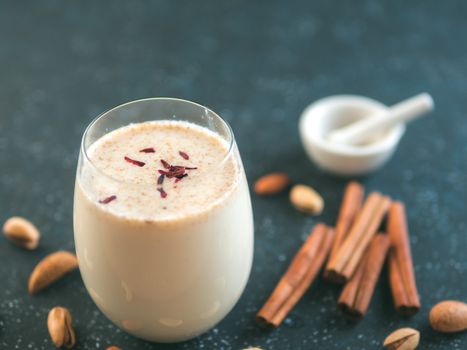 Thandai or Sardai cold drink made during Holi festival. Cold milk drink in glass, with ingredients - nuts and spices. Copy space