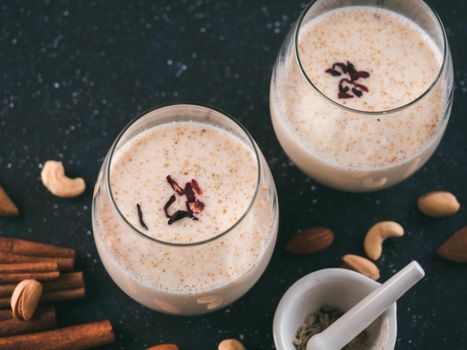 Thandai or Sardai cold drink made during Holi festival. Cold milk drink in glass, with ingredients - nuts and spices. Copy space