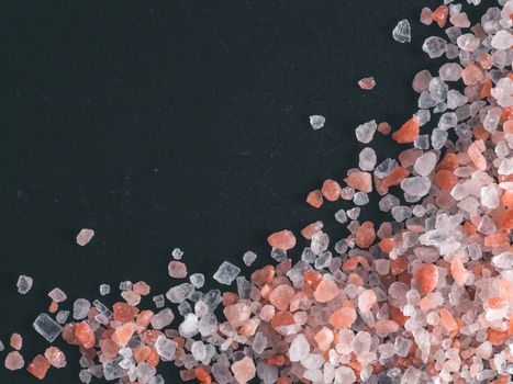 Himalayan pink salt in crystals on black stone background. Copy space