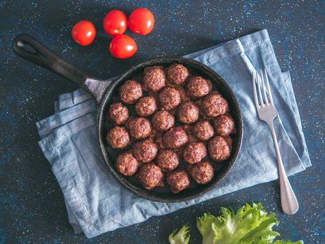 Homemade roasted beef meatballs in cast-iron skillet on dark blue background. Top view or flat-lay. Copy space for text.