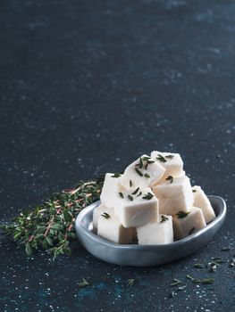 Greek cheese feta with thyme on dark blue table. Copy space