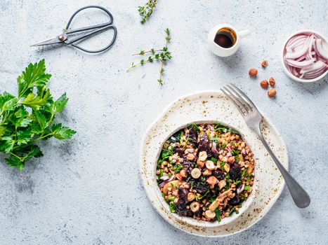 Warm buckwheat and beetroot salad on gray background. Vegetarian diet idea and recipe -salad with beetroot, buckwheat, mushrooms, onion, fresh herbs,hazelnut. Top view or flat-lay. Copy space for text