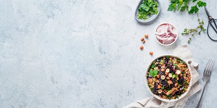 Warm buckwheat and beetroot salad on gray background. Vegetarian diet idea and recipe -salad with beetroot, buckwheat, mushrooms, onion, fresh herbs,hazelnut. Top view or flat-lay. Copy space for text