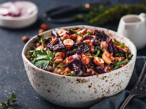 Warm buckwheat and beetroot salad on dark background. Vegetarian diet idea and recipe -salad with beetroot, buckwheat, mushrooms, onion, fresh herbs,hazelnut. Copy space for text