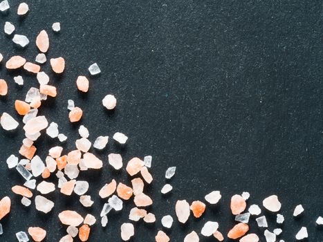 Himalayan pink salt in crystals on black stone background. Copy space