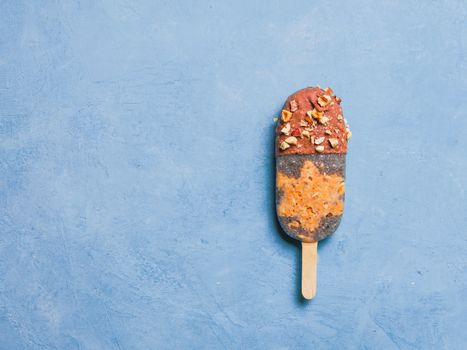 Chia popsicle with raw carrot cake and chocolate on blue background. Healthy recipe and idea homemade vegan popsicle ice cream. Easter dessert idea. Copy space for text. Top view or flat-lay.