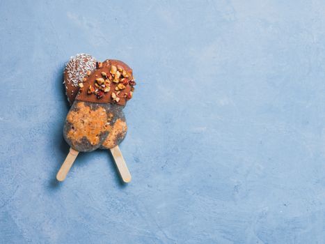 Chia popsicle with raw carrot cake and chocolate on blue background. Healthy recipe and idea homemade vegan popsicle ice cream. Easter dessert idea. Copy space for text. Top view or flat-lay.