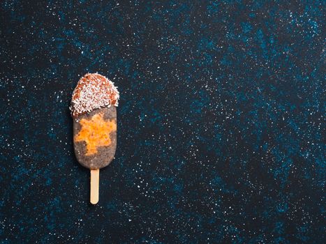 Chia popsicle with raw carrot cake and chocolate on dark blue background. Healthy recipe and idea homemade vegan popsicle ice cream. Easter dessert idea. Copy space for text. Top view or flat-lay.