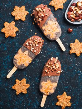 Chia popsicle with raw carrot cake and chocolate on dark blue background. Healthy recipe and idea homemade vegan popsicle ice cream. Easter dessert idea. Top view or flat-lay. Vertical.