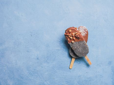 Chia popsicle with chocolate on blue background. Healthy recipe and idea homemade vegan popsicle ice cream. Easter dessert idea. Copy space for text. Top view or flat-lay.