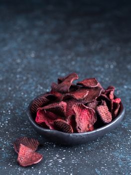 Baked beet slices. Healthy homemade beetroot chips in plate on dark blue background. Copy space
