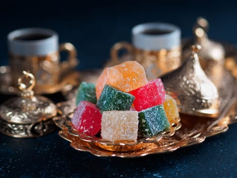 Turkish coffee with delight and traditional copper serving set on dark background. Assorted traditional turkish dilight or lokum and turkish coffee in metal traditional cups.Copy space.Selective focus