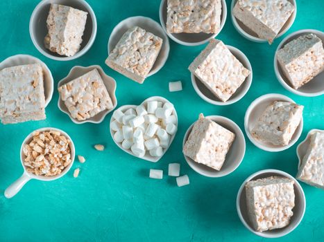 Homemade square bars of Marshmallow and crispy rice and ingredients on azure blue background. American dessert with marshmallow and crispy rice. Top view. Copy space