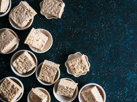 Homemade square bars of Marshmallow and crispy rice and ingredients on dark blue background. American dessert with marshmallow and crispy rice. Top view. Copy space