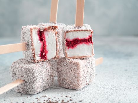 Homemade raw lamington ice cream pops on gray background. Australian sweet dessert lamington with chia and raspberries jam, chocolate and cocoa coat. Vegan food recipe and idea. Copy space for text