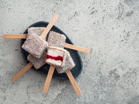 Homemade raw lamington ice cream pops on gray background. Australian sweet dessert lamington with chia and raspberries jam, chocolate and cocoa coat. Vegan food recipe and idea. Copy space. Top view