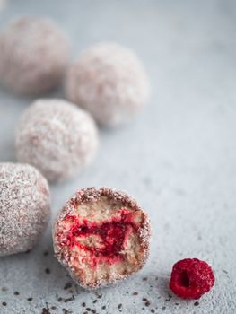 Raw vegan lamington bliss balls with raspberries chia jam on gray background. No baked healthy vegan sweet dessert idea and recipe. Copy space for text.