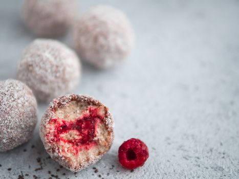 Raw vegan lamington bliss balls with raspberries chia jam on gray background. No baked healthy vegan sweet dessert idea and recipe. Copy space for text.