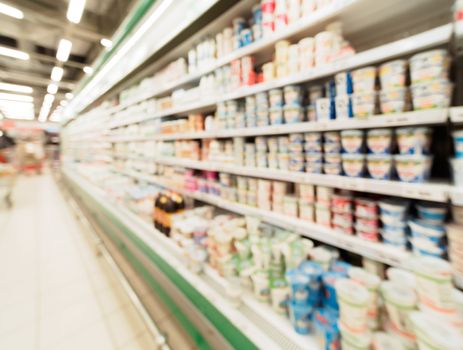 Defocused blur of supermarket shelves with dairy and mayonnaise products in refrigerator. Blur background with bokeh. Defocused image
