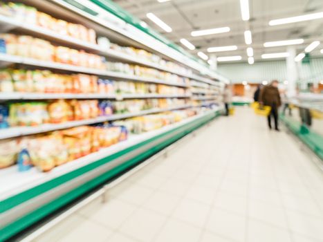 Defocused blur of supermarket shelves with dairy and mayonnaise products in refrigerator. Blur background with bokeh. Defocused image