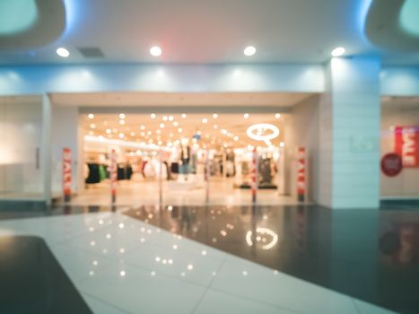 Shopping mall blur background with bokeh. Abstract blurred entrance area of clothes and shoes store. Copy space