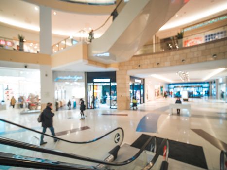 Shopping mall blur background with bokeh. Blurred hall of shopping mall with customers as background. Copy space