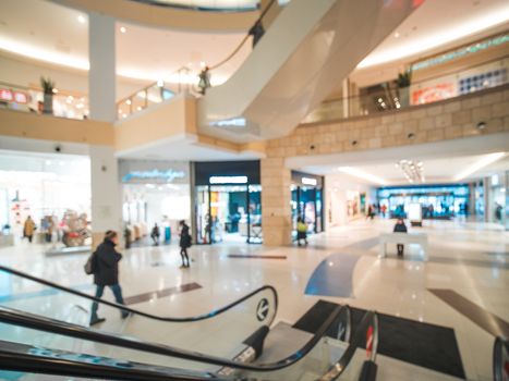 Shopping mall blur background with bokeh. Blurred hall of shopping mall with customers as background. Copy space