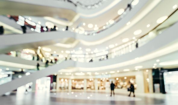 Beautiful image of modern shopping mall, blur background with bokeh. Blurred hall of shopping mall with customers as background. Copy space