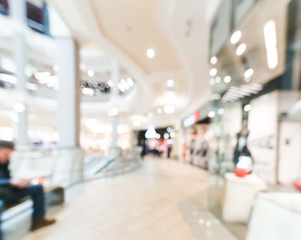 Shopping mall blur background with bokeh. Blurred hall of shopping mall with customers as background. Copy space